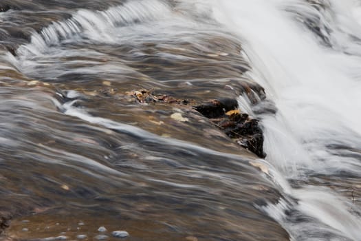 Beautiful small waterfalls of a fast moving creek in fall