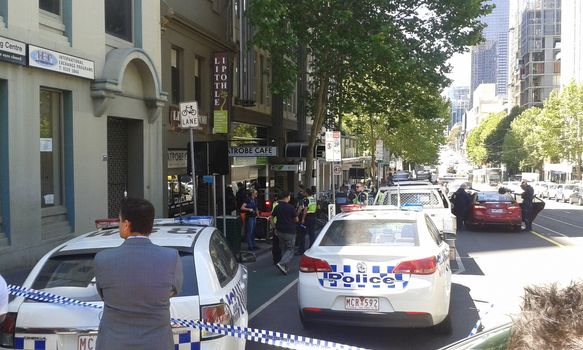 AUSTRALIA, Melbourne: Police in Victoria surround a man after he was seen shouting and waving a meat cleaver on La Trobe Street, in Melbourne on October 27, 2015. The man refused to cooperate and was been seen smashing windows and throwing things at police. Photo shows police just arriving to set up cordon.