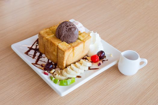 Honey toast and whipping cream with chocolate ice cream on wood background