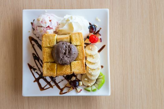 Honey toast and whipping cream with chocolate ice cream on wood background
