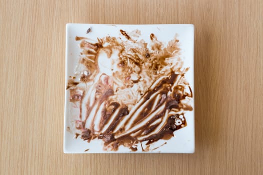 Leftovers of food on the white modern plate on wood background