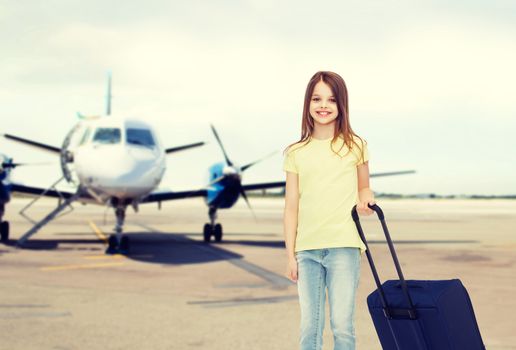 tourism, holiday, vacation, childhood and transportation concept - smiling little girl with travel bag over airport background