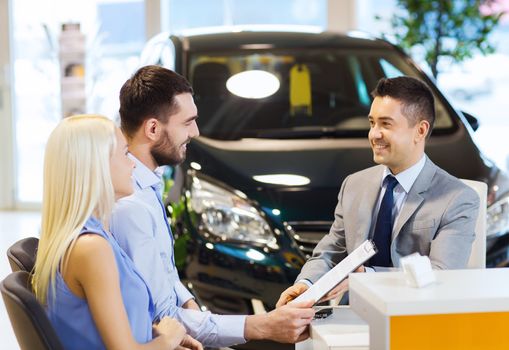 auto business, sale and people concept - happy couple with dealer buying car in auto show or salon