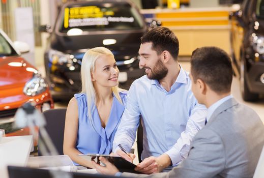 auto business, sale and people concept - happy couple with dealer buying car in auto show or salon