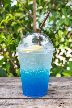 blue lemon soda on wood table with green leaves background, be fresh in nature