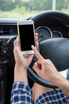 Young female driver using touch screen smartphone in a car.