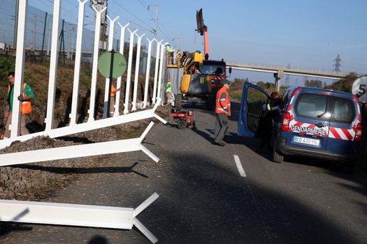 FRANCE, Calais: Police officers watch as workers install new fences around the French entrance of the Channel Tunnel in Calais, northern France, on October 26, 2015. Since the beginning of the migrants crisis, railway company Eurotunnel has reinforced its security measures, including installing new fences to avoid migrants enter the site.