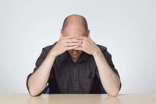 stressed man looking down at desk