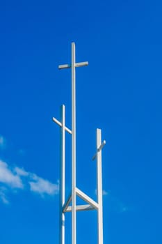 Three trinity White Christian crosses in front of a cloudy sky with copyspace