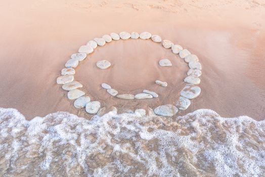 Emoticon of pebbles on the sandy beach