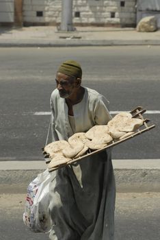 LUXOR, EGYPT - AUGUST 03, 2006: The unknown person carries grain flat cakes in the Luxor market. Luxor - the city in the Top Egypt and the capital of Luxor of Governorate.