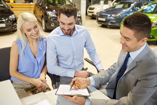 auto business, sale and people concept - happy couple with dealer buying car in auto show or salon