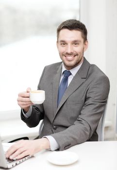 office, business, technology and internet concept - smiling businessman with laptop computer and coffee at office