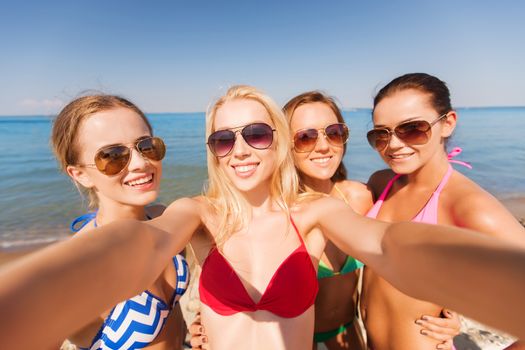 summer vacation, holidays, travel and people concept - group of young smiling women photographing by camera or smartphone on beach