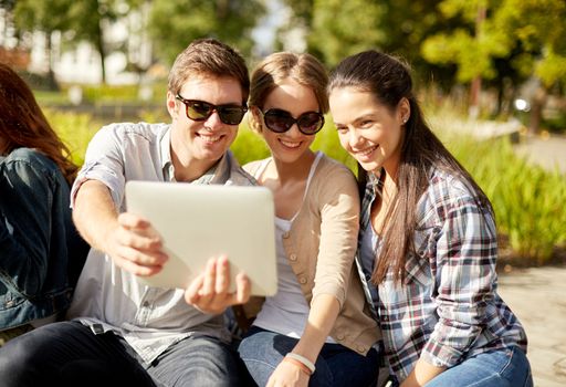 summer, education, technology and people concept - group of students or teenagers with laptop computers sitting on bench outdoors