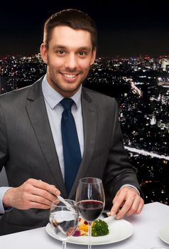 restaurant, people and holiday concept - smiling man eating main course at restaurant