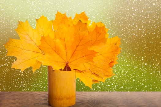 bouquet of yellow maple leaves in a wooden vase