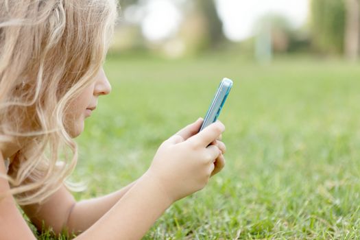 blond baby girl outdoors with a mobile phone