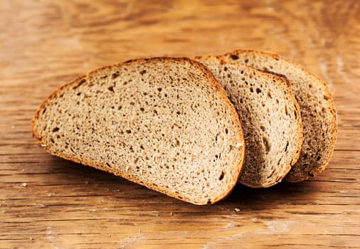 Three sliced rye bread on a wooden background