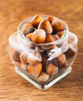 hazelnuts in a glass jar on a wooden background