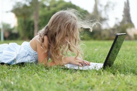 blond baby girl with laptop outdoors