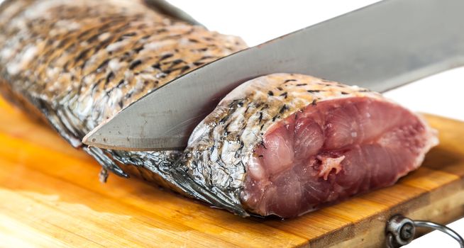 part of the fish lying on the kitchen board with knife