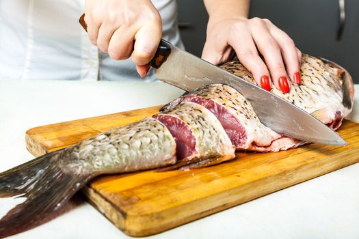 girl with a kitchen knife cut the fish into slices