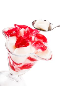 vanilla and red jelly in a glass goblet on a white background
