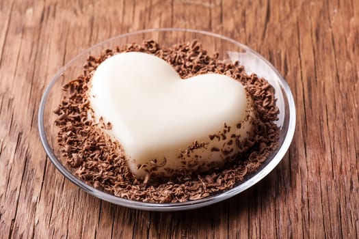 jelly in the form of heart on a glass saucer close-up on wooden background