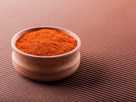 paprika in a wooden bowl on a brown background