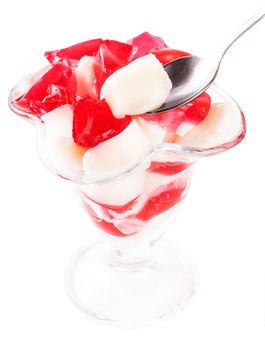 cubes of vanilla and red jelly in a glass goblet on a white background