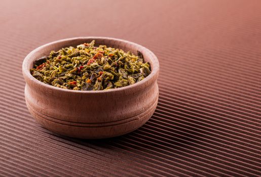 green pepper in a wooden bowl on a brown background