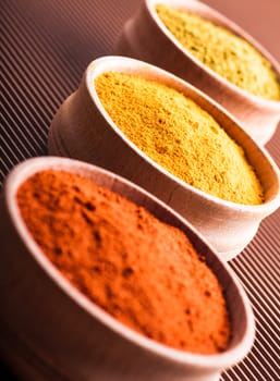 hops-suneli,turmeric,paprika in a wooden bowl close-up on a brown background