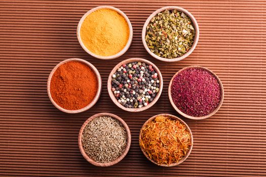 set dry spices in a wooden bowl on a brown background