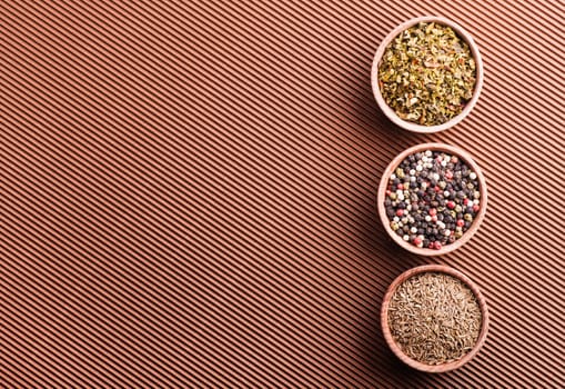 pepper,cumin,paprika in a wooden bowl on a brown background