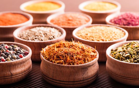 assorted spices in a wooden bowl close-up on a brown background