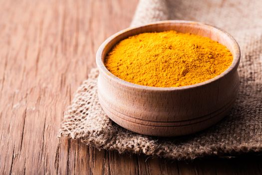 dry spice turmeric in a wooden bowl close-up on a vintage background