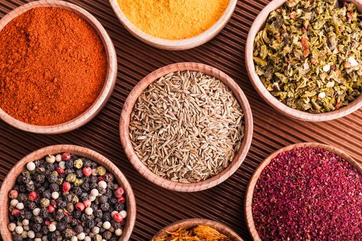 set dry spices in a wooden bowl close-up on a brown background