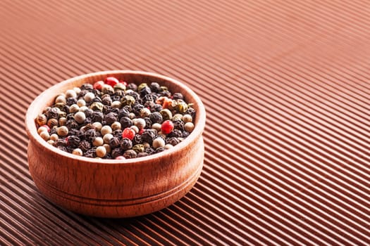 spice assorted pepper in a wooden bowl on a brown background