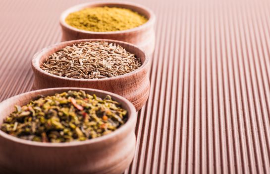 cumin,hops-suneli,paprika in a wooden bowl close-up on a brown background