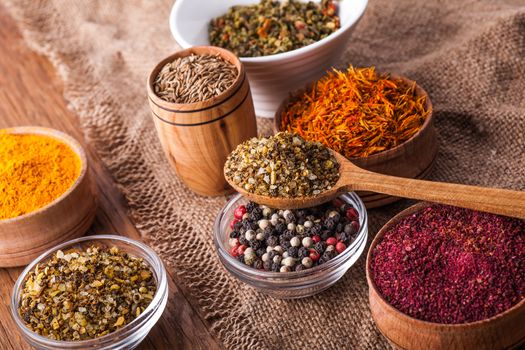 dry spices in a wooden and glass bowls on a vintage background