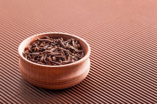 clove in a wooden bowl close-up on a brown background