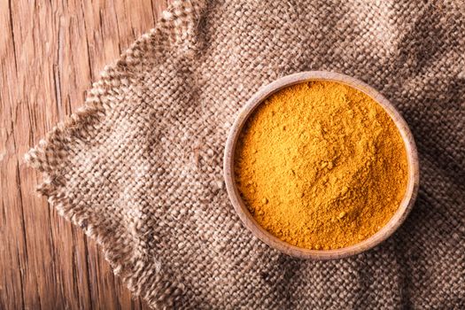 dry spice turmeric in a wooden bowl on a vintage background