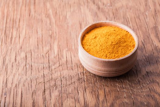 spice turmeric in a wooden bowl on a vintage background