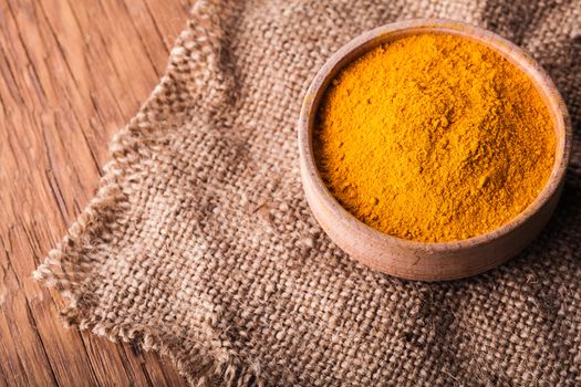 dry turmeric in a wooden bowl close-up on a vintage background