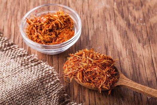 spices saffron in a glass bowl and spoon on a vintage background