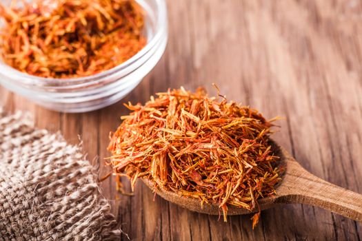 spices saffron in a glass bowl and spoon close-up on a vintage background