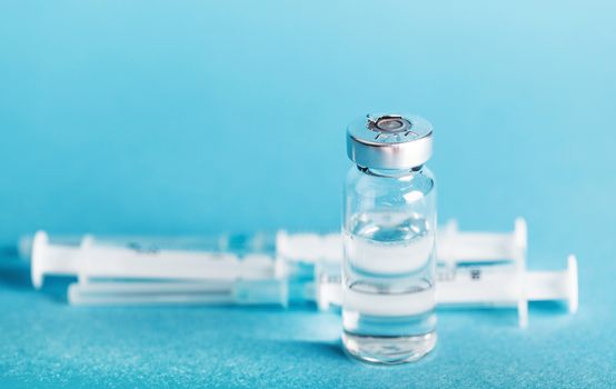 vial medicines and syringe on a blue background