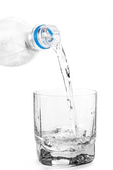 into the glass water is poured on white isolated background