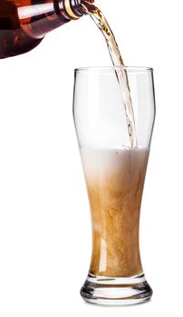 into the glass beer is poured on white isolated background